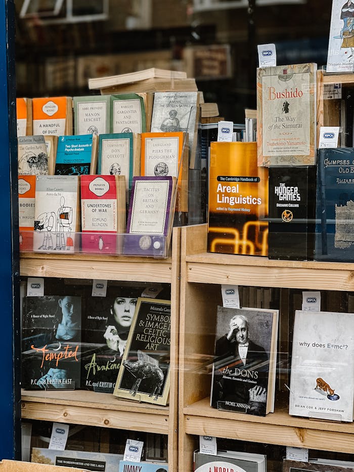 A diverse collection of books displayed in a bookstore window, showcasing various genres and authors.