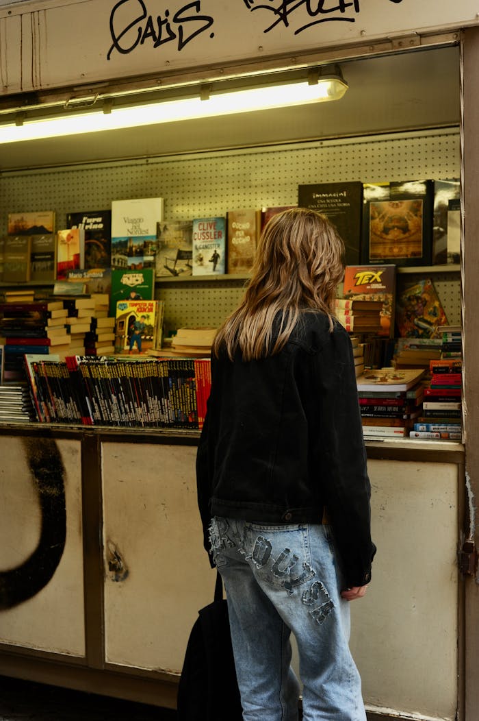 A person exploring book offerings at an outdoor bookstore in Venice, Italy.