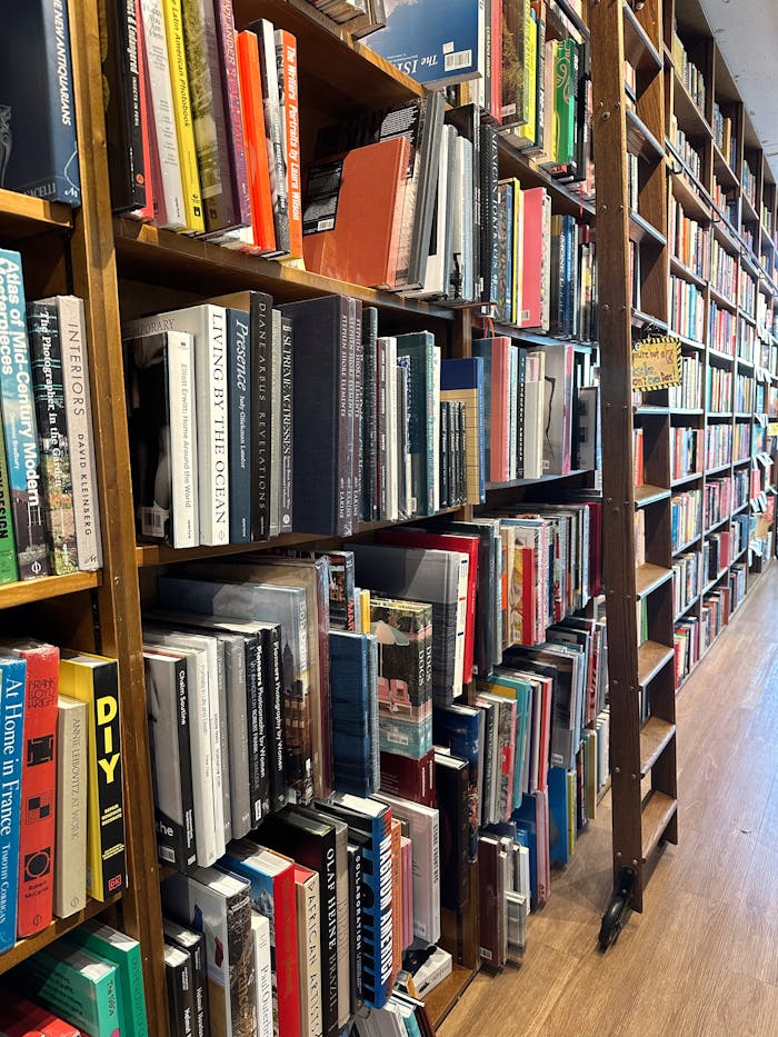 Warm and inviting aisle in a bookstore filled with colorful books on wooden shelves.